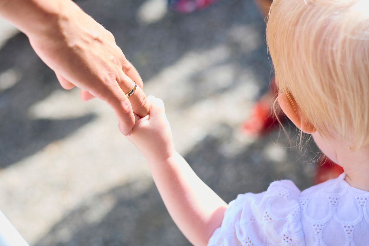 Mastering the First Impression: Your intriguing post title goes here Blonde child holding parent's hand outdoors, symbolizing love and protection.