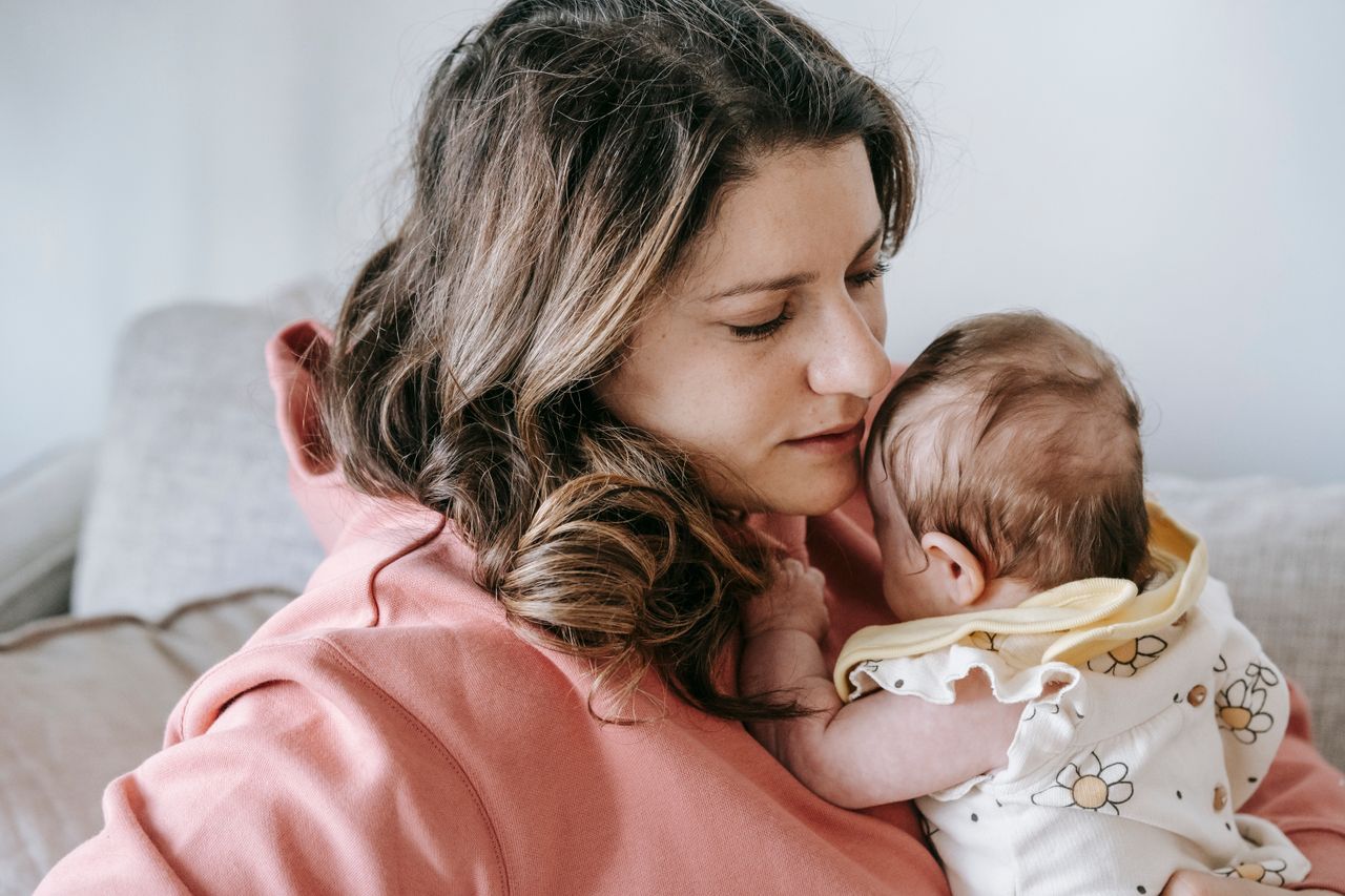 Crafting Captivating Headlines: Your awesome post title goes here Side view of caring mother in casual clothes with adorable infant in arms sitting on comfortable sofa in light room at home