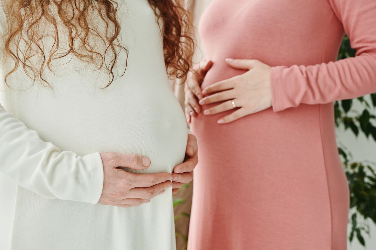 about-02 Two expectant women gently holding their pregnant bellies, symbolizing motherhood and maternity.